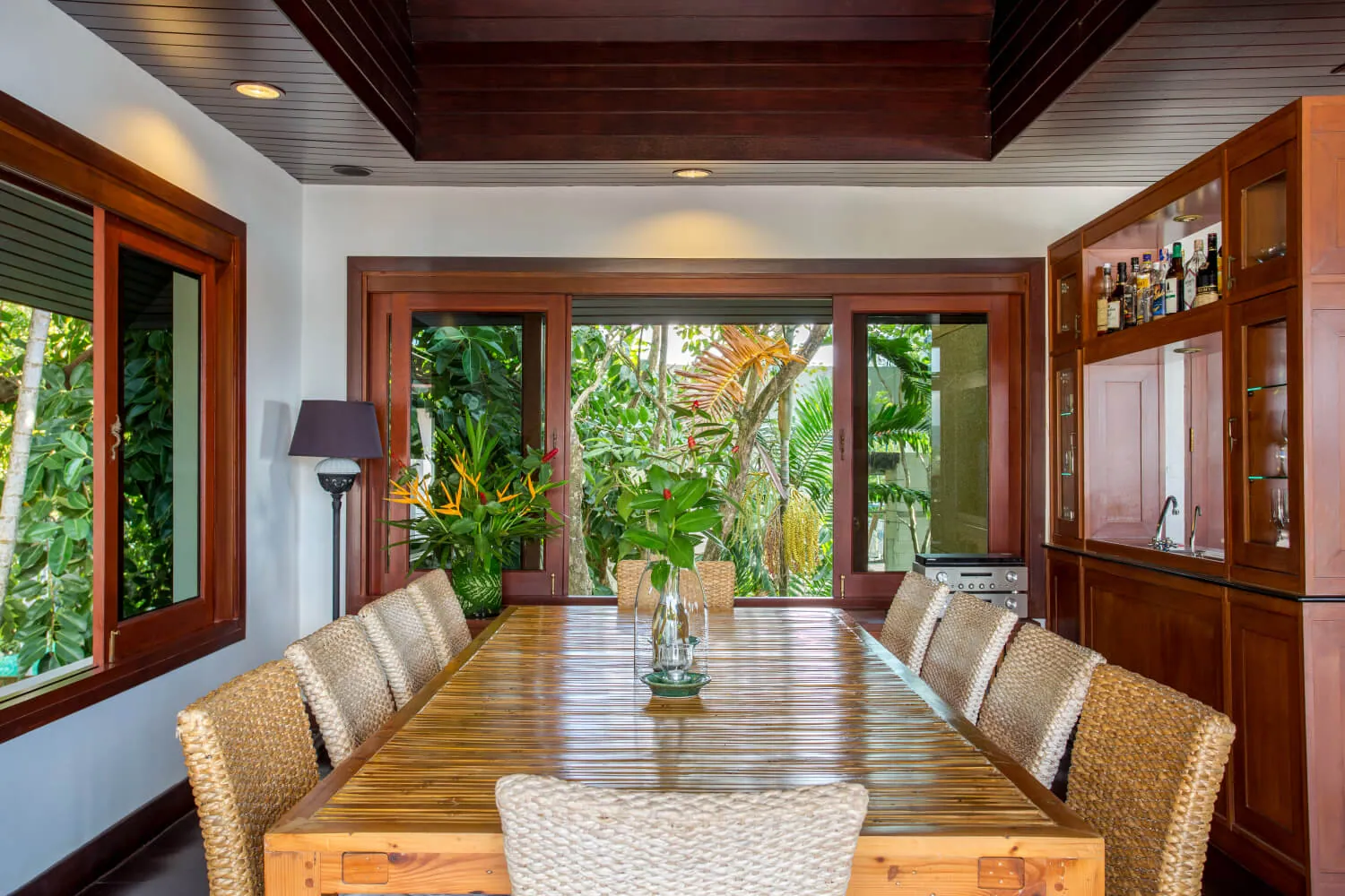 The indoor dining table set for ten under the teak ceiling