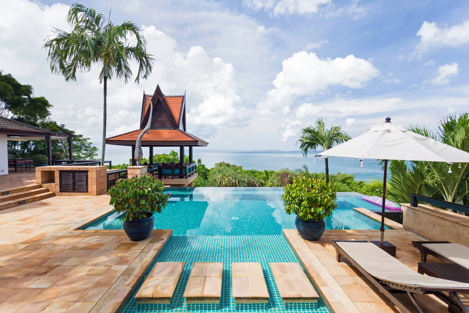 The pool terrace, loungers and the sea beyond